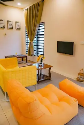 a living room with an orange couch and a tv at Wewe Homestay in Kampung Gajah
