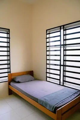 a bed in a room with two large windows at Wewe Homestay in Kampung Gajah