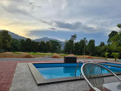 a swimming pool with a chair next to a table at D Tasek Homestay Lenggong