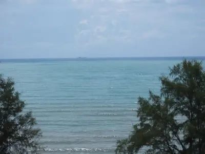 a view of the ocean with trees in the foreground at Ferringhi Luxury Suite @ By The Sea in Batu Ferringhi