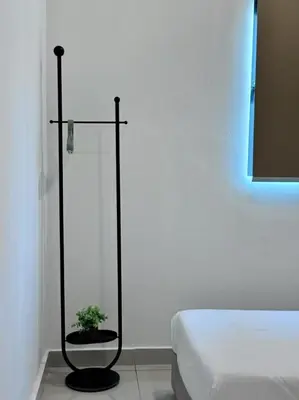 a black stand next to a bed with a potted plant at Warm & Cozy Home in Kampong Duson Gilap