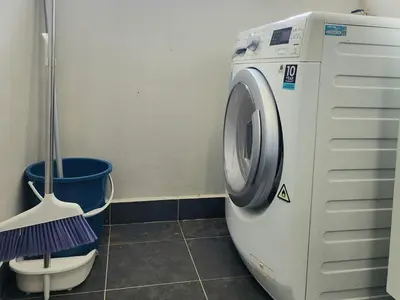 a washing machine in a bathroom with a bucket at Stylish Living 2BR Suite in George Town