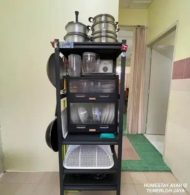 a shelf with a microwave and pots and pans at Homestay Ayah Iz Temerloh Jaya in Gua Sai