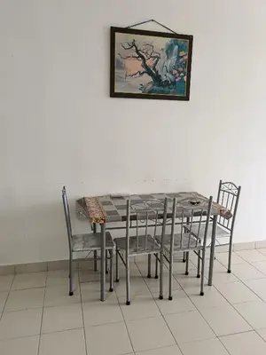 a dining room table with chairs and a painting on the wall at Little sweet in Gua Sai