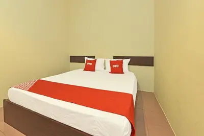 a bedroom with a large bed with red pillows at SPOT ON 91178 Motel Impian in Kampong Telok Batu