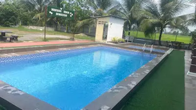 a large swimming pool with blue water and palm trees at Capital O 91180 Mentari Senja Homestay in Kampong Dekeh