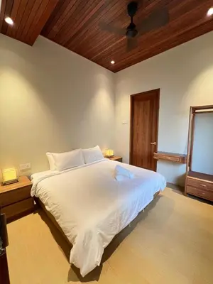 a bedroom with a white bed with a wooden ceiling at Shinju Villa with Jacuzzi Pool in Jelutong