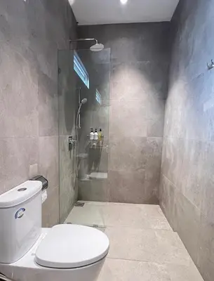 a bathroom with a toilet and a glass shower at Shinju Villa with Jacuzzi Pool in Jelutong