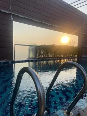 a swimming pool with a sunset in the background at Woodsbury Suites Butterworth in Butterworth