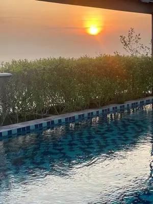a swimming pool with a sunset in the background at Woodsbury Suites Butterworth in Butterworth