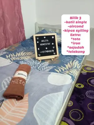 a table with a sign and a bed with a bedspread at Auliya Homestay in Gua Sai
