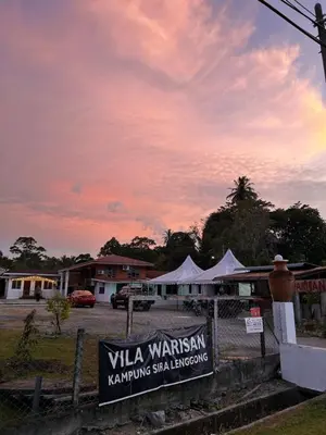 a sunset with a sign in front of a building at Villa Warisan Homestay