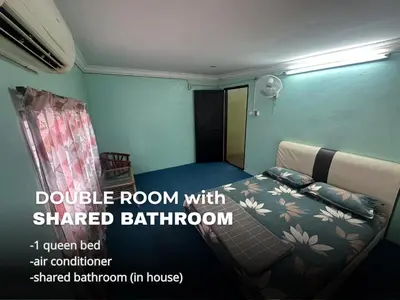 a room with a bed with a shared bathroom at Villa Warisan Homestay