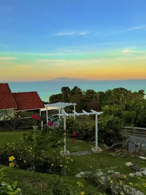 a white pergola in a yard with a view of the ocean at VELAMUNDi INN Batu Ferringhi in Batu Ferringhi