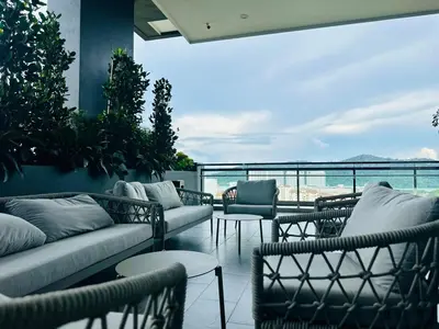 a patio with couches and tables and a view of the ocean at New LuxurySuite Rooftop Pool Stunning View airport 9pax in Bayan Lepas