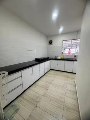 a kitchen with white cabinets and a woman in a window at Homestay Dmickey in Sungai Petani