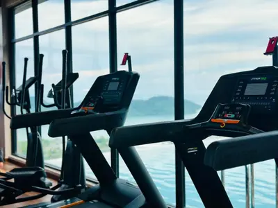 a row of cardio machines in a gym with a view of the water at Iconic Regency bayan lepas 42 skypool airport usm 9pax in Bayan Lepas
