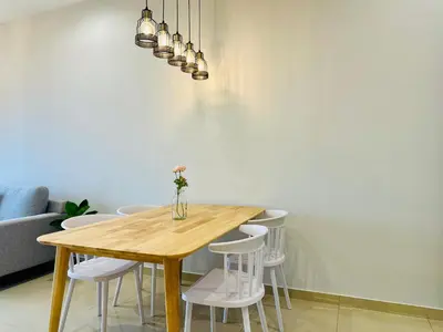 a dining room table with white chairs and a vase on it at High Rise Haven 3BR Rooftop Pool Stylish Comfort 9pax in Bayan Lepas