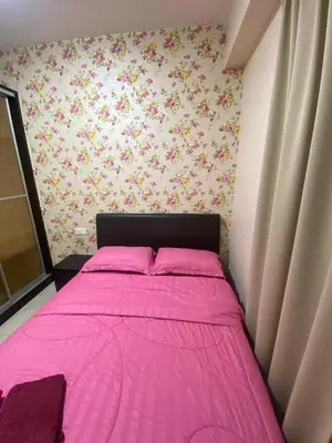 a pink bed in a small bedroom with flowers on the wall at 11th Sky Kinta Riverfront with Wi-Fi in Ipoh