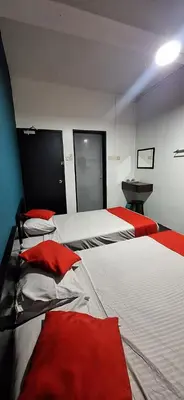 a room with two beds with red sheets and a table at Captain Hotel Cafe & Bistro in Sitiawan