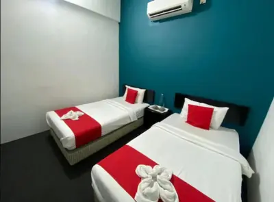 two beds in a room with red and white at Captain Hotel Cafe & Bistro in Sitiawan