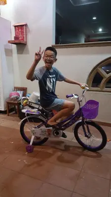 a young boy is sitting on a bike at alor satar in Gua Sai
