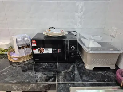 a microwave on a counter with a plate on top at NAR Kampung Studio in Bayan Lepas