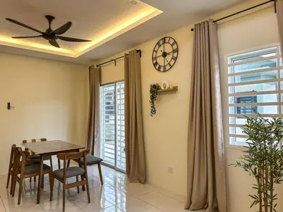 a dining room with a table and a clock on the wall at Hana Homestay Seri Iskandar in Seri Iskandar