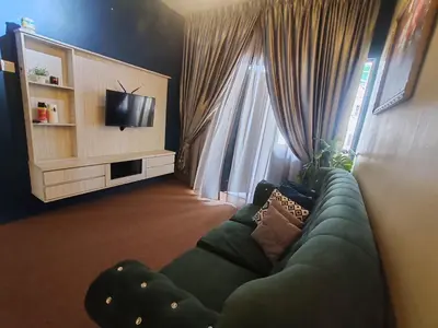 a living room with a green couch in front of a window at ZE I Cameron Jaya, Tanah Rata in Tanah Rata