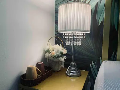 a lamp on a table with a vase of flowers at Cozy Private Room Teluk Intan in Teluk Intan
