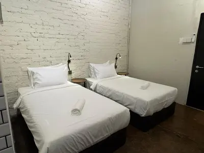 two beds in a hotel room with white sheets at Miner's House Ipoh in Ipoh