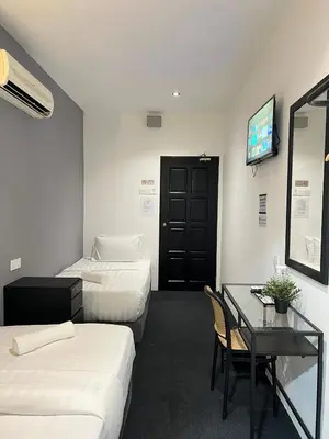 a hotel room with two beds and a desk and a television at Quee Hotel in George Town