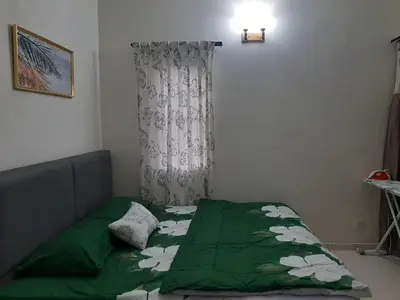 a bedroom with a green comforter on a bed at MK Homestay Sunway in Ipoh