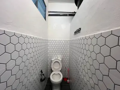 a bathroom with a toilet in a white tiled wall at Vintage Comfort 3Bedroom Haus in Lunas