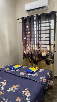 a bedroom with a bed with a blue blanket and a window at Capital O 91191 Chalet Cd Impiana in Kulim