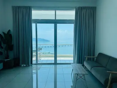 a living room with a couch and a view of the ocean at Southbay Seaview Condo A31 #10minQueensbay in Bayan Lepas