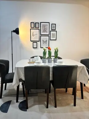 a dining room with a table with chairs and flowers on it at Dandelion 3BR Apt Near lake garden in Taiping