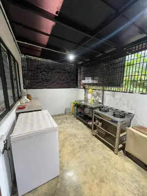 a kitchen with a stove and a table in it at Laman Serambi Homestay in Hutan Melintang