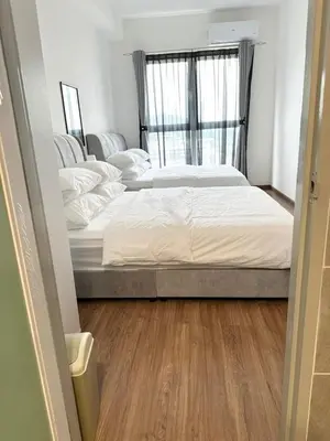 two beds in a small room with wood floors at ICC Suites Ipoh 16th floor in Ipoh