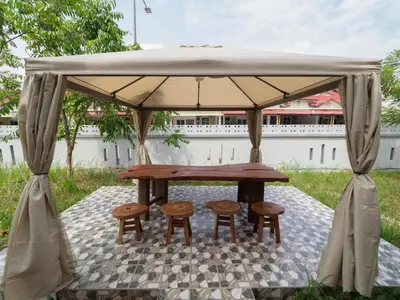 a picnic table and two stools under a canopy at D SeBalik Pulau Tropical Boutique Home in Balik Pulau