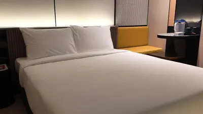 a bed with white sheets and pillows in a room at Urban Inn, Cengal Jaya in Sungai Petani