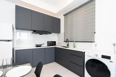 a kitchen with black cabinets and a washer and dryer at Creamy French at Urban Suite in George Town