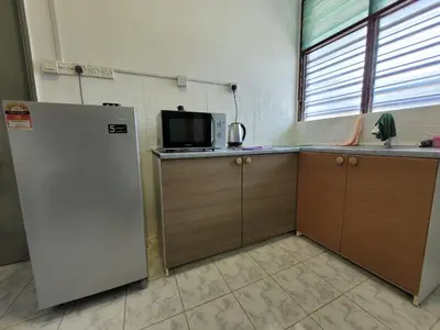 a kitchen with a refrigerator and a microwave at Ria Serene Homestay in Sungai Petani