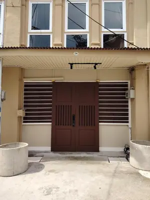 a garage with a brown door and two windows at Mokū Georgetown Pre-war House 4BR 5-14pax in George Town