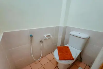 a bathroom with a toilet with a orange towel on it at Virgo Batik Resort, Teluk Batik in Lumut