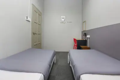 two beds in a room with white walls at Bed Station Guest House in Tanah Rata