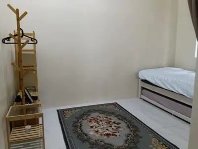 a room with a rug on the floor next to a bed at Homestay Omah D'Desa with pool in Kampong Telok Ru