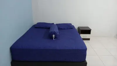 a blue bed with a blue comforter and pillows at Eyna Homestay in Sitiawan