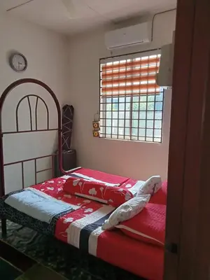 a bedroom with a bed with a red blanket and a window at Homestay Mariah in Ipoh