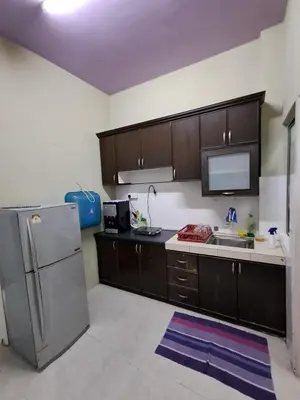 a kitchen with wooden cabinets and a stainless steel refrigerator at Serra Homestay at Apartment Bukit Permata, Lumut in Lumut